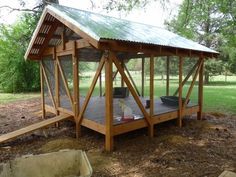 a chicken coop in the middle of a field with trees and grass behind it,