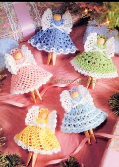 small crocheted angels are sitting on a pink blanket next to pine cones and christmas decorations