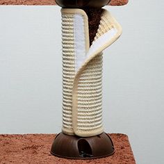 a brown and white cat sitting on top of a scratching tower with its tail curled up