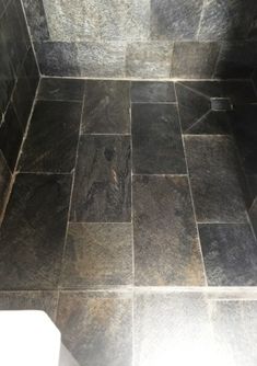 a tiled shower stall with black and white tile on the floor, walls and ceiling