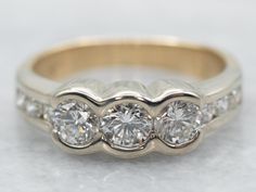 a three stone diamond ring on a white surface