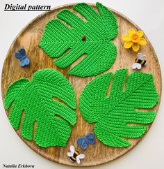 a wooden plate topped with green leaves and flowers