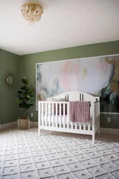 a baby's room with a large painting on the wall and a white crib