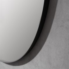 a white and black computer mouse sitting on top of a gray surface with shadow from it