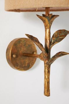 a wall light with a tree design on the front and back of it's arm