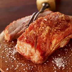 two pieces of meat sitting on top of a wooden cutting board