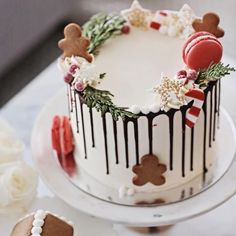 a decorated christmas cake sitting on top of a white table next to cookies and flowers