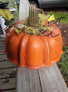 a pumpkin shaped planter sitting on top of a wooden bench next to a car