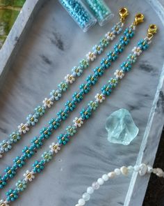 the beads are laying next to each other on the marble tray with two gold - plated clasps