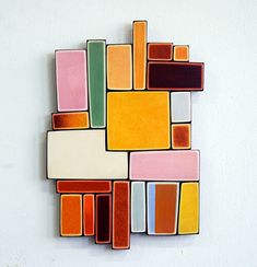 a colorful piece of art hanging on the side of a wall with squares and rectangles