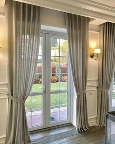 a living room filled with furniture next to a large window covered in white drapes