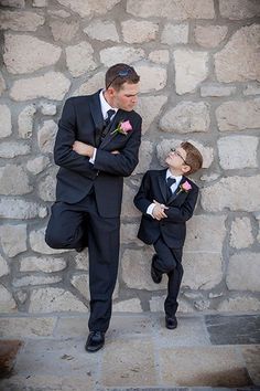 a man in a suit and tie standing next to a little boy wearing a tuxedo