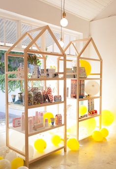 a display case with yellow balloons in the shape of a house and some bookshelves