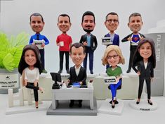 a group of bobble heads sitting on top of a white table next to each other