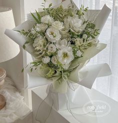 a bouquet of white flowers sitting on top of a table next to a window sill