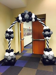 an entrance decorated with balloons and black and white decorations for a graduation party or celebration