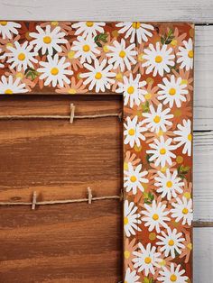 a wooden frame decorated with daisies and twine