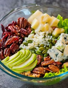 a glass bowl filled with nuts, cheese and other food items on top of a table