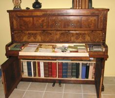 an old wooden piano with many books on the top and bottom shelf next to it