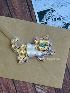 an envelope with a cat embroidered on the front and back side, sitting on a wooden table