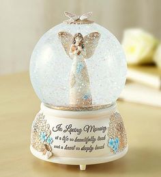 a snow globe with an angel figurine in it sitting on a wooden table