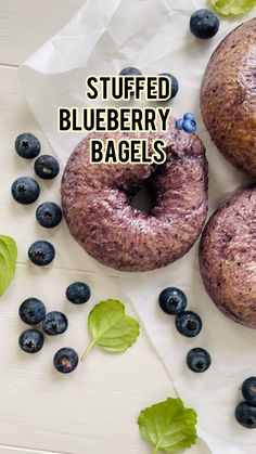 three blueberry bagels are sitting next to some leaves