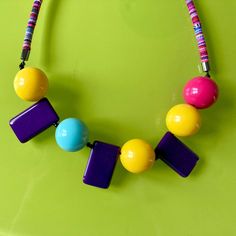 Necklace with round and rectangular beads. Vibrant colors like yellow, pink and light blue are balanced by darker lacquered purple beads. Mainly in acrylic, it is mounted on a colored cotton cord matching the beads. Delivered in a pretty fabric pouch. Adjustable Multicolor Rectangular Beaded Necklaces, Large Rectangular Multicolor Beads, Fabric Pouch, Purple Beads, Pretty Fabric, Necklace Unique, Cotton Cord, Unique Necklaces, Unique Pieces