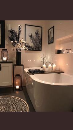 a white bath tub sitting in a bathroom next to two candles and pictures on the wall