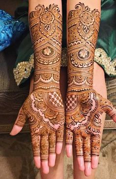 two hands with henna tattoos on them, one is showing off the intricate design