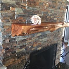 a stone fireplace with a wooden mantle and decorative item on it's mantle top