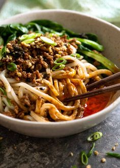 a close up of a bowl of food with chopsticks