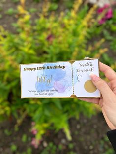 someone holding up a birthday card in front of some flowers