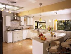 a large kitchen with white cabinets and marble counter tops, along with an island in the middle