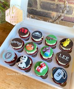 twelve cupcakes are arranged in a box on a table next to a brick wall