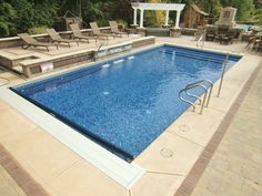 an empty swimming pool with lounge chairs and fire pit in the backround area