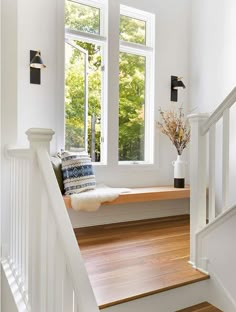 there is a window seat on the stairs in this house with wood flooring and white walls