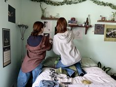 two women sitting on top of a bed next to each other in a room with green walls