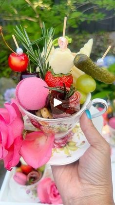 a person holding up a cup filled with different types of fruit and veggies