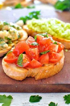 an open face sandwich with tomatoes, lettuce and other toppings on a cutting board