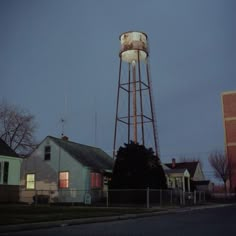 an old water tower sits in the middle of a neighborhood at night with no one around it