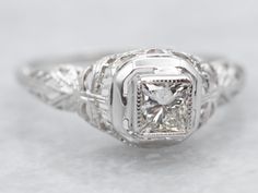 an antique style diamond ring with filigrees on the sides and center stone