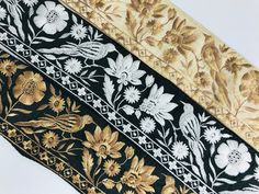 three pieces of black and white fabric with gold floral designs on the sides, one is yellow