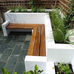 a wooden bench sitting in the middle of a garden next to a planter filled with potted plants