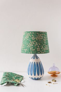 a blue and white vase sitting on top of a table next to a green lamp