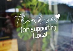 there is a sign that says thank you for supporting local businesses on the window sill