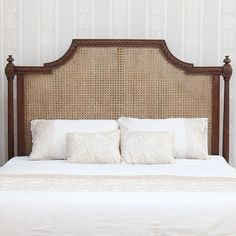 a bed with two pillows on it in front of a wallpapered headboard