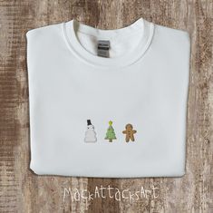 It's the holiday season and that means it's time to get festive with some Christmas themed apparel for you and your family! This Cozy sweater features a Christmas tree with some little red lights, a snowman that you'll create yourself this holiday season, and a gingerbread man that you'll munch on the night of the holiday festivities! This shirt is perfect for the minimalist in your family, or even yourself. The design is simple, trendy, and cute! ABOUT * 50% cotton, 50% polyester * Pre-shrunk * Classic fit * 1x1 athletic rib knit collar with spandex * Air-jet spun yarn with a soft feel and reduced pilling * Double-needle stitched collar, shoulders, armholes, cuffs, and hem MANUFACTURING: This product is made especially for you as soon as you place an order, which is why it takes us a bit Christmas White Embroidered Tops, Embroidered Christmas Holiday Tops, Holiday Cotton Top With Embroidery, Holiday Cotton Embroidered Tops, Christmas Minimalist, Snowman Sweater, Red Lights, Christmas Feeling, Sweatshirt Christmas