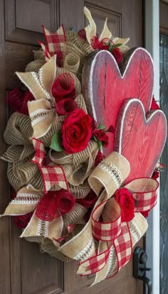 a wreath with two heart shaped red roses on it and burlocks attached to the front door