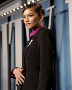 a woman in a black suit and pink shirt