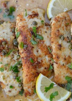 two pieces of fish with lemons and capers on top